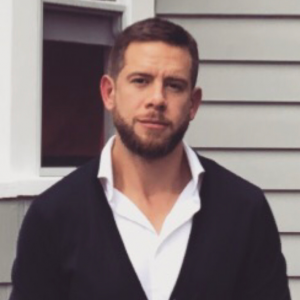 Declan looking directly at camera in front of a grey house.