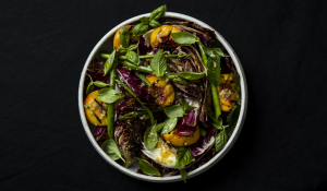 Radicchio, peach and asparagus salad in a bowl, against a dark tablecloth.