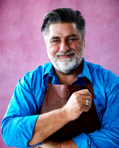Matt Preston smiling in front of a pink background.