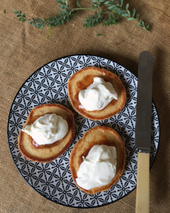  Delicious looking pikelets viewed from the top down, with jam and cream on top.